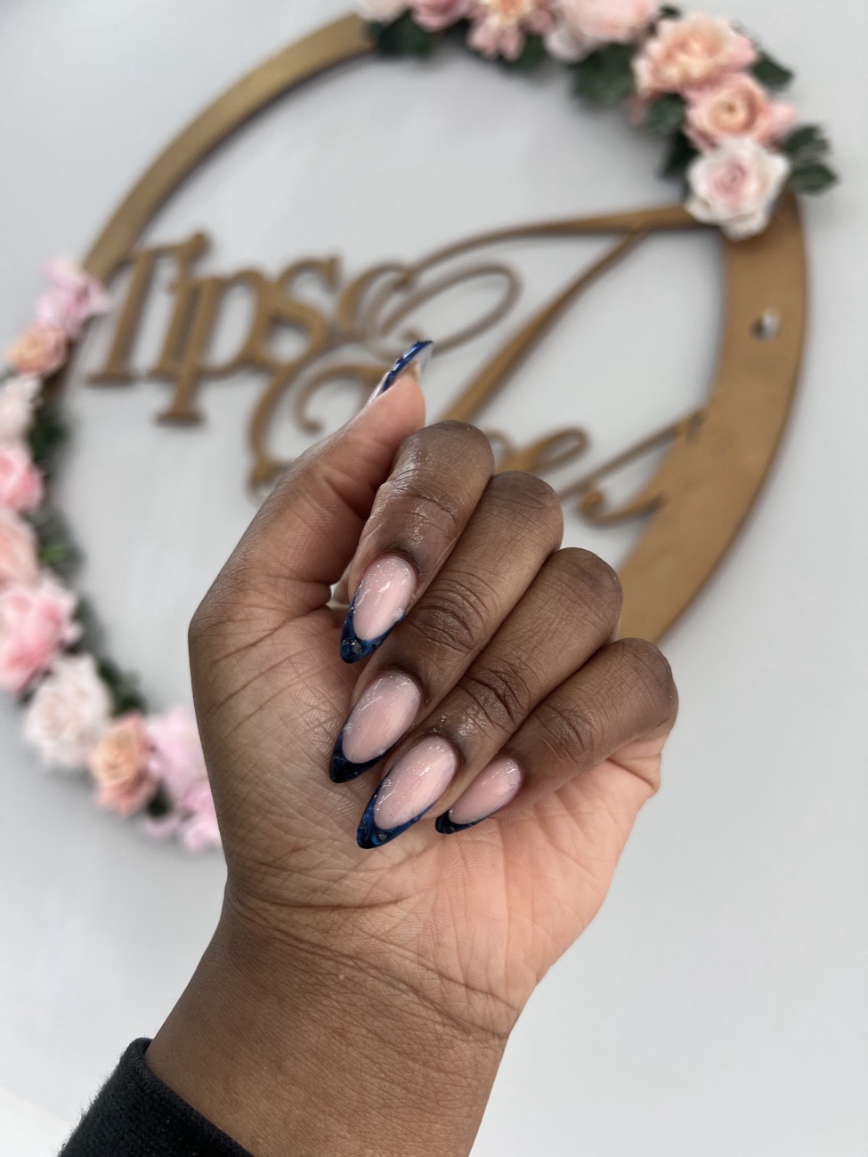 Navy marble French almond nails in front of the Tips and Toes salon sign